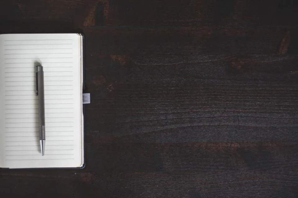 Notebook and pen on a dark wooden desk