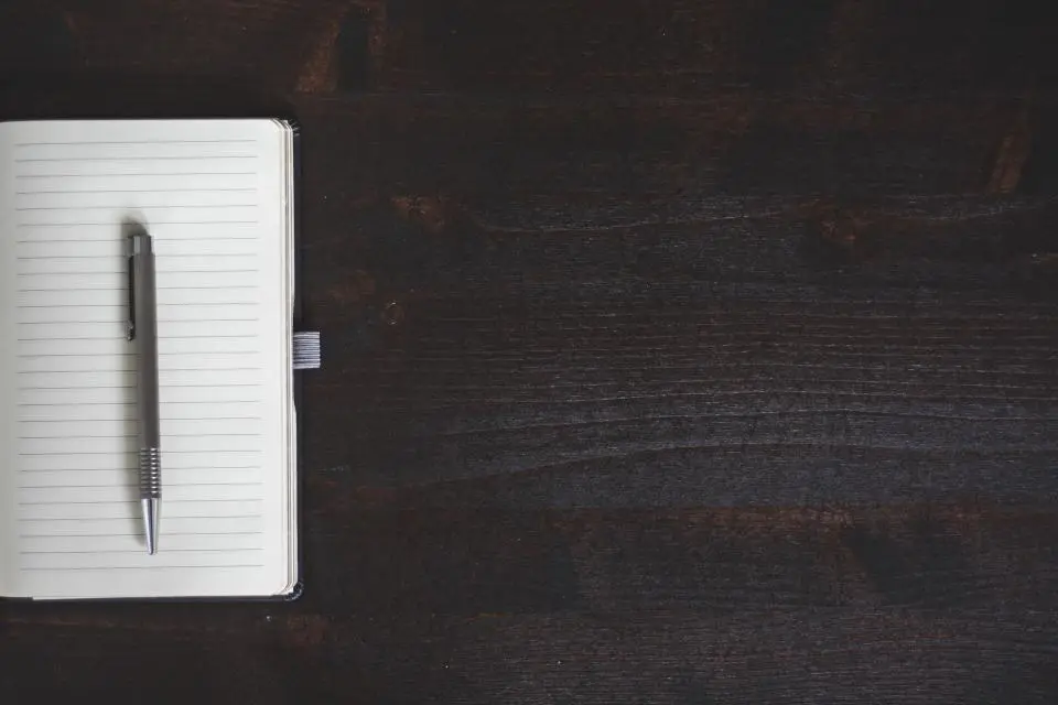 Notebook and pen on a dark wooden desk